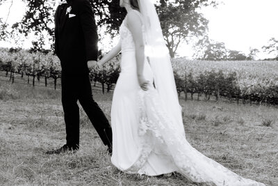 bride and groom walking through vineyard with a blurry vibe