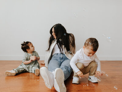 Mom sits with kids on the floor playing with bubbles