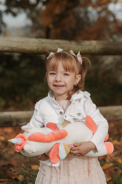Little girl holding a unicorn stuffie.