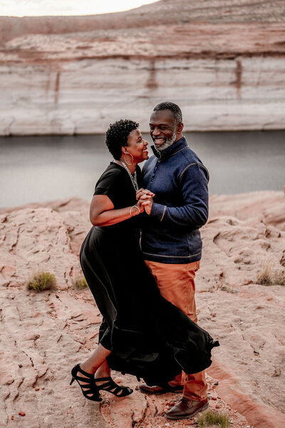A couple enjoying a romantic engagement proposal amidst the scenic beauty of Lake Powell, surrounded by dramatic rock cliffs and turquoise waters.