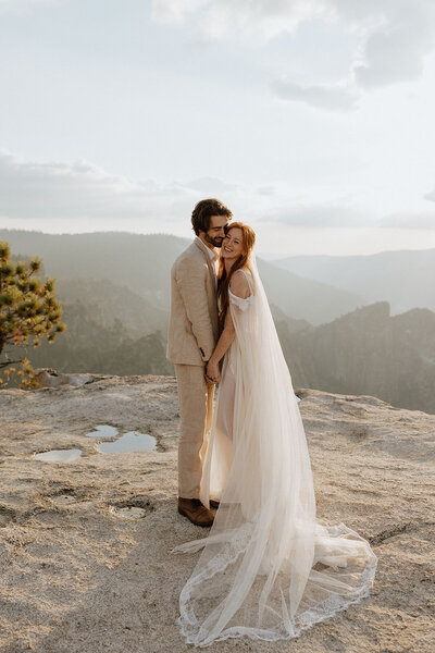 bride and groom happy and embracing on a rocky overlook