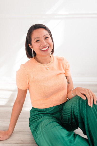 woman sitting on the ground leaning back on one hand with the other resting on her knee