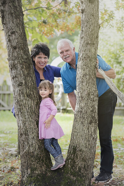 Two people standing next to a tree with a small child standing in between them