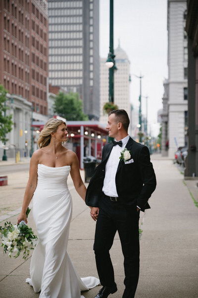 Indoor wedding ceremony at The Arbor Loft, featuring whitewashed brick walls, hanging greenery, and guests seated in rows.