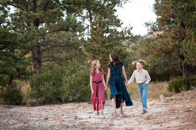 A teen girl holds hands and walks with her younger brother and sister