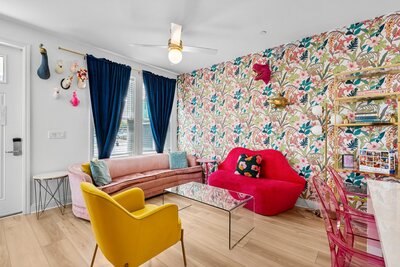 Bright entryway and cozy living room with eclectic wall decor and plush furniture, welcoming guests to a fun-filled stay near 30A and Santa Rosa Beach.