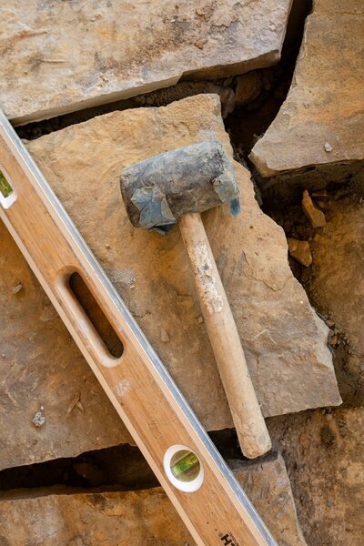 Close-up of stone pavers with a mallet and level, showing tools used during hardscape installation by Better Lawns and Gardens in Little Rock, Arkansas.

