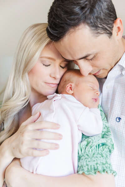 Mom and dad snuggling newborn baby girl during lifestyle newborn session in their home