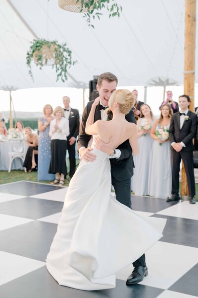 First dance captured at a stunning wedding reception at the Eisenhower House in Newport, Rhode Island. The bride and groom share a magical moment on the dance floor, surrounded by guests in elegant attire. Felisha, a destination wedding photographer based in New England, specializes in capturing intimate wedding moments in Rhode Island, Boston, New England, and worldwide locations.