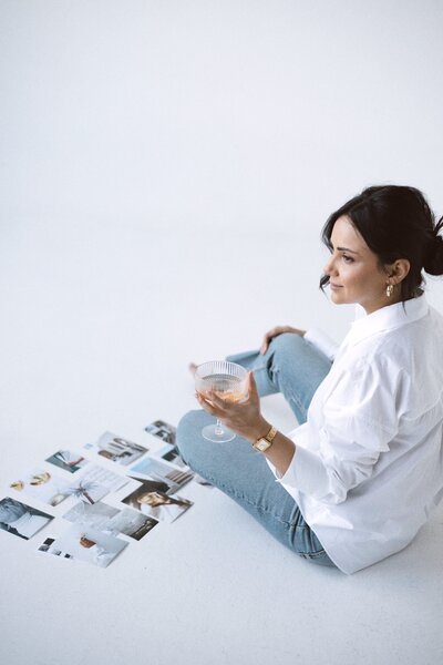 Amare Creative's brand styling: Various photos artfully arranged on the ground, complemented by a girl joyfully sipping champagne, creating a chic and vibrant atmosphere.