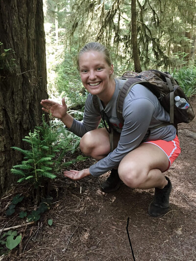 girl showing off a baby tree in the forest
