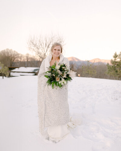 Couple is kissing dip style pose in the snow at a venue. 