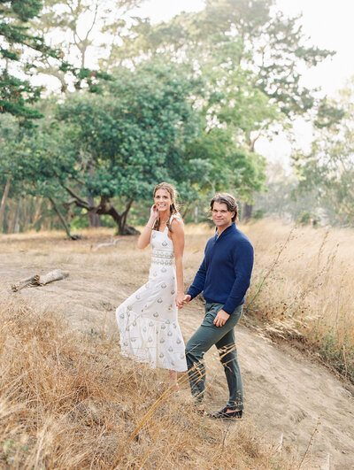 Engagement photography of a man and women sitting side by side on a cement step, in front of an old Italian style blue and orange argyle pattern painted cement wall.