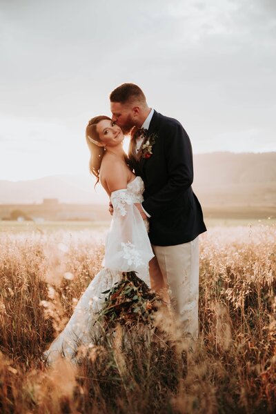 Bride and groom smiling in field