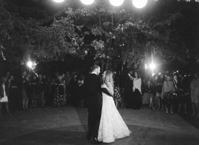 Husband and wife dance to their wedding beat at a dimly illuminated wedding reception party.