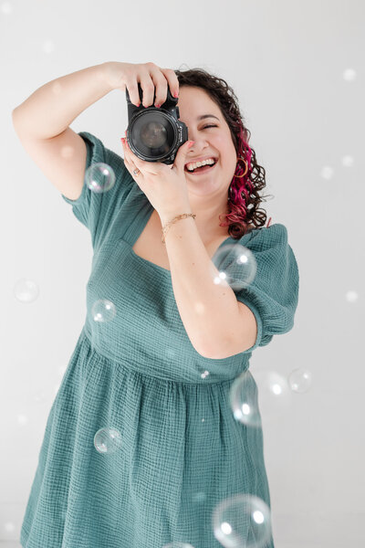 Laura smiles while taking a photo, surrounded by bubbles