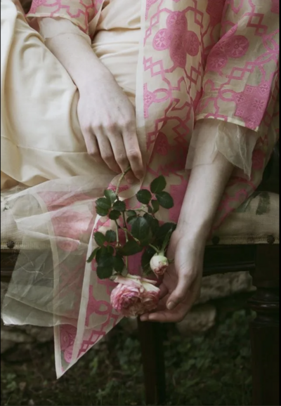 An image of a woman in a pink robe holding a pink rose