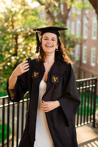 Girl wearing Vanderbilt cap and gown laughing at camera