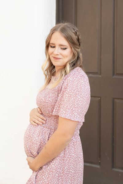 Mother holding her baby bump smiling off to the side