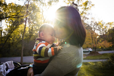 HIXON FOREST - LA CROSSE, WISCONSIN - DOCUMENTARY FAMILY PHOTOGRAPHY SESSION - MOM HOLDING BABY IN SUNLIGHT