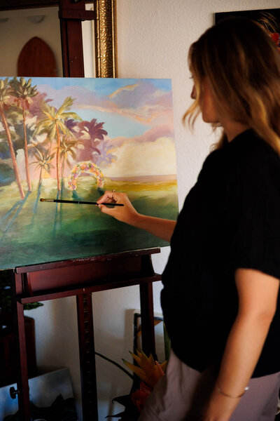 Artist paints a tropical wedding scene live, including purple sunset hues, palm trees, and the floral ceremony arch