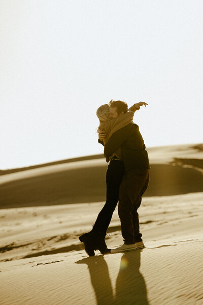 A couple hugging each other on a windy day at Silver Lake Sand Dunes