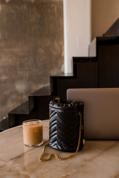 Black bag and candle on brown marble table