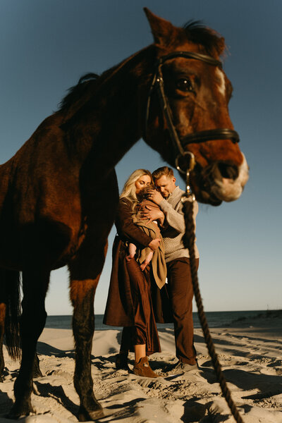 Family embracing in a golden field during an outdoor fall photography session in Stanhope, NJ, with warm, natural tones and scenic hills in the background, captured by Burkat Photography.

