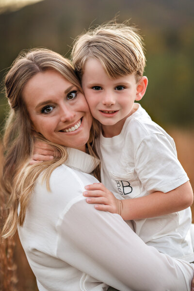 A mom and her young son smile for the camera at their mother and son photoshoot.