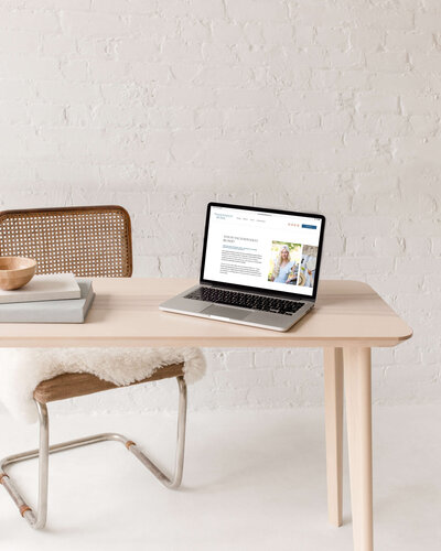Website design for blogger and female creative, laptop sitting on table with cane chair