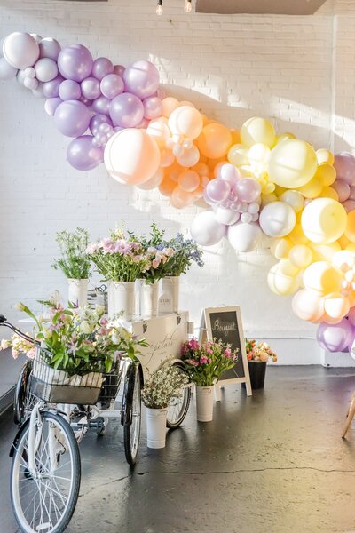 Elegant balloon arch with floral bicycle cart