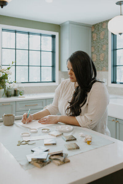 An artist with long dark hair drawing in a blue and green studio
