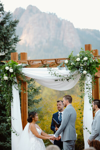 Bride and groom smiling at each other in Rocky Mountain National Park, Estes Park, Colorado, with mountain peaks in the background.