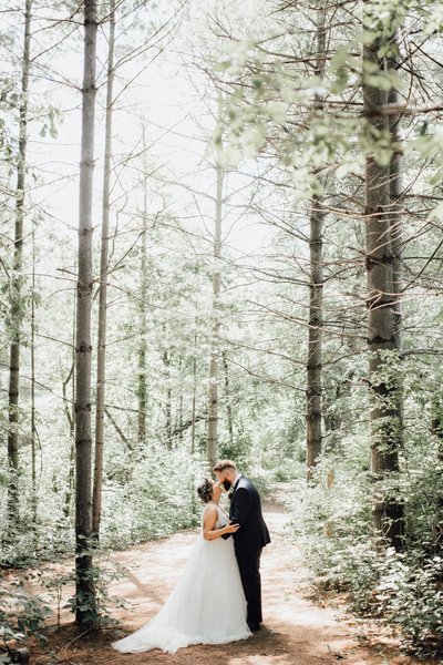 kortright center bride and groom kissing in forest