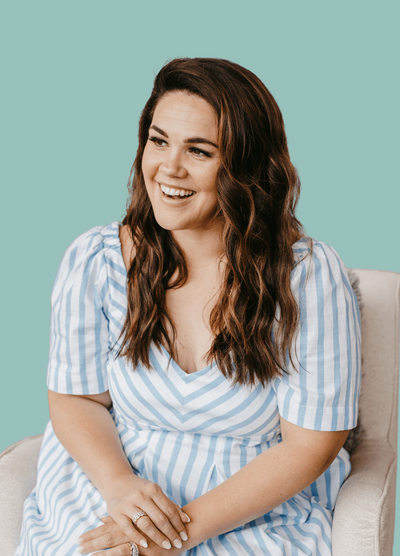 Woman with dark hair in white and blue striped dress sitting down
