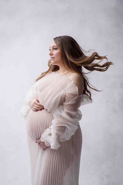 Seattle Photographer Captures pregnancy photo of mom with wind-swept hair pleated white chiffon dress fine art style image