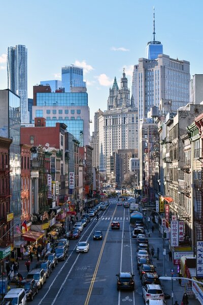 Busy street scene in Chinatown, NYC with shops and traffic.