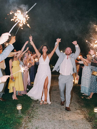 Black and white photo of bride and groom in their getaway car waving and surrounded by bubbles