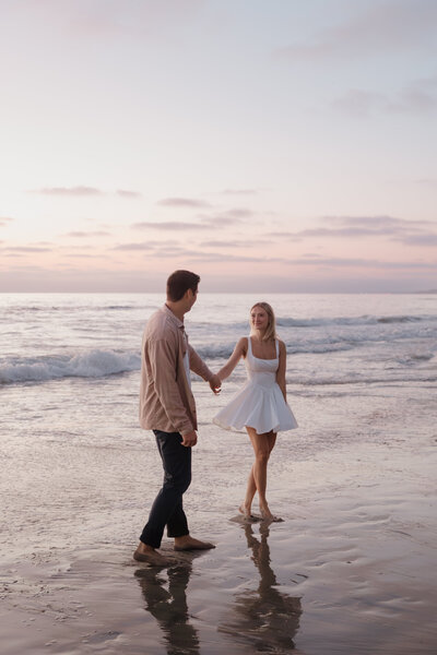 Couple looking at each other photography poses during sunset at Scripps Pier in La Jolla California 