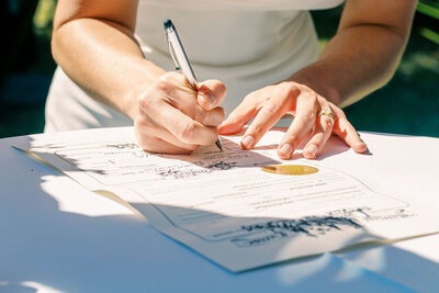 Close-up of a bride signing the marriage license on her wedding day, captured by Joseph Mayden to document authentic and meaningful moments in natural light.