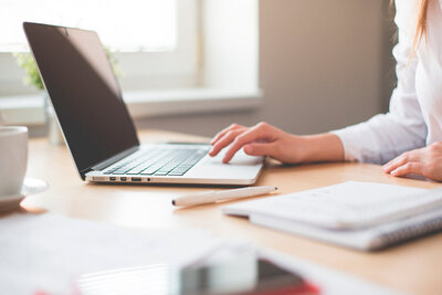 A professional providing corporate financial consulting services in Dallas, working on her laptop in a financial office. The setting highlights the provision of additional business services to support corporate clients.