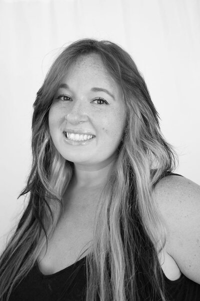 Black and white photo of woman with shoulder-length dark hair softly smiles.