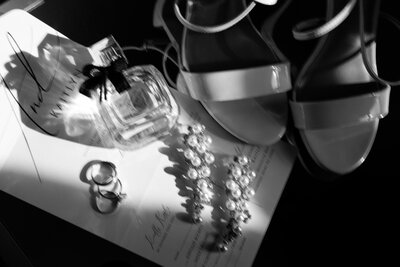 Black & white detail photo of bridal shoes, rings, and earrings.