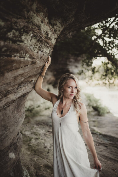 Caroline leaning against a cliff, embodying trust, inner strength, and connection to earth energy.