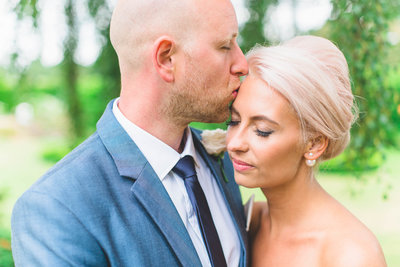 a relaxed wedding photography portrait of a groom kissing the brides forehead - by cheshire wedding photographer