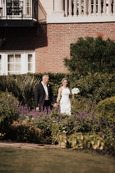 Bride and groom coming out of hotel and walk through gardens