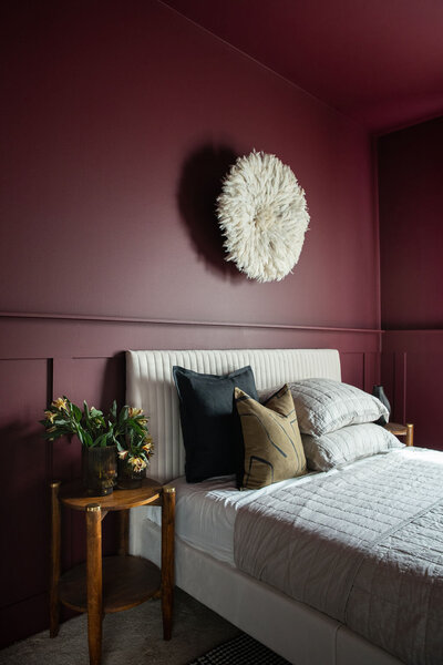 a bedroom with neutral furniture and bold red walls