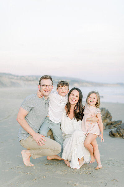 Connecticut photographer, Kristin Wood, smiles with her husband and two children during beach family portrait session
