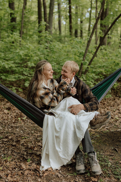bride and groom cuddled up in a hammock laughing