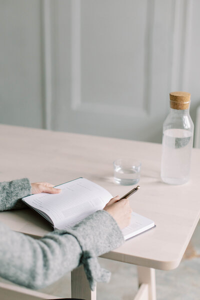 A woman writing in her journal, reflecting on personalized wellness strategies and exploring the mind-body connection.